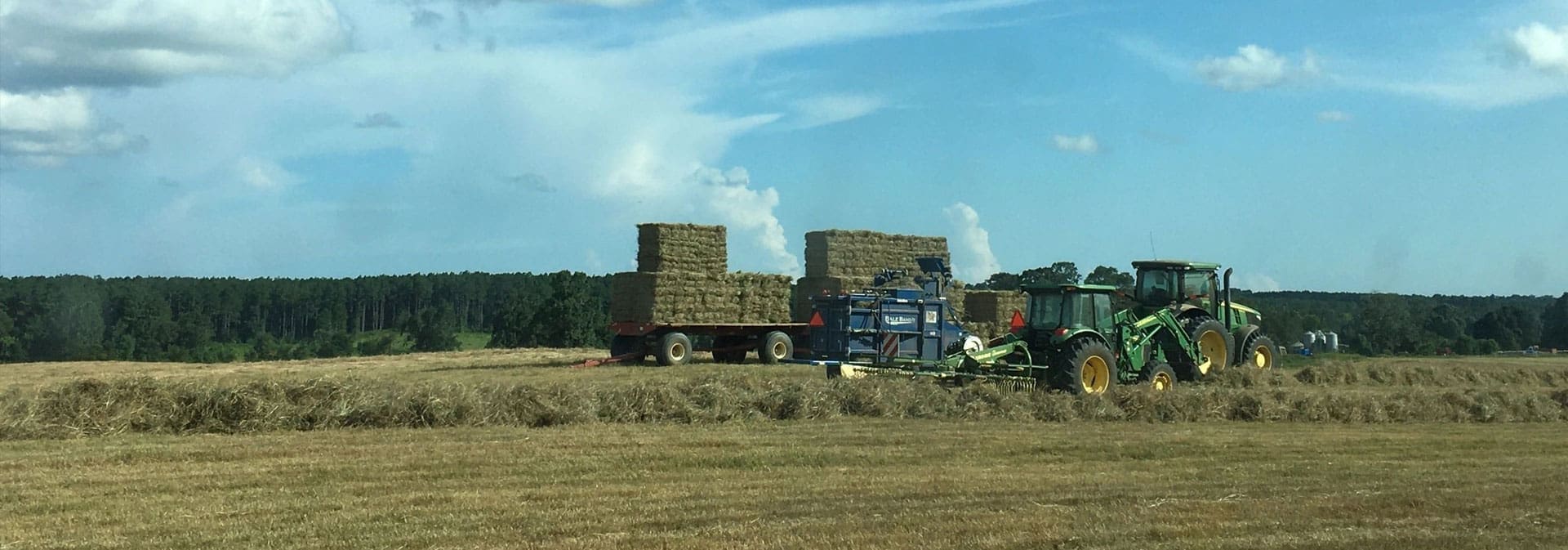 A tractor pulling hay bales in the middle of a field.
