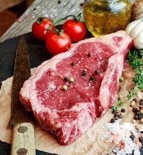 A piece of meat on top of a cutting board.