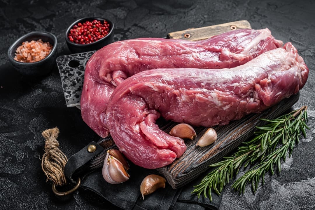 A wooden cutting board with meat on it.